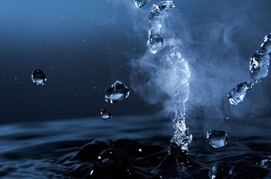 Tropfen von Thermalwasser fallen in dunkles Wasser