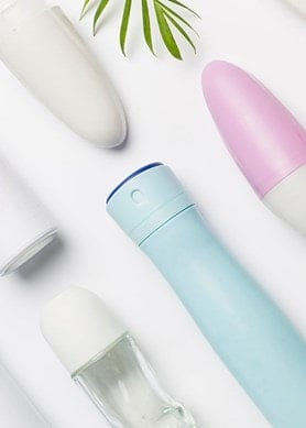 Auswahl verschiedener Deoarten – Roll-ons, Sprays und Sticks – auf weißem Tisch arrangiert.