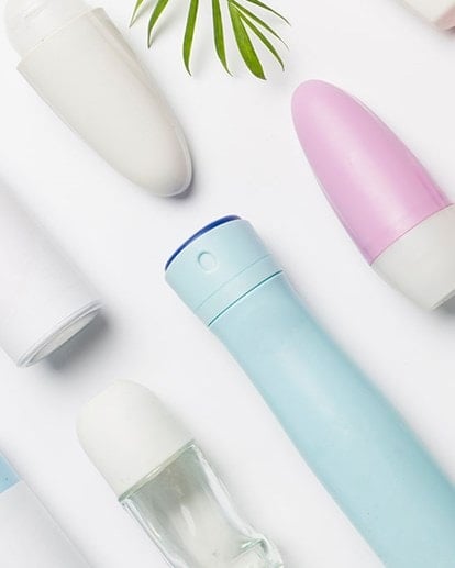 Auswahl verschiedener Deoarten – Roll-ons, Sprays und Sticks – auf weißem Tisch arrangiert.