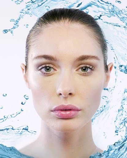 Frau mit frischer Haut, umgeben von Wasserspritzern – Symbol für intensive Feuchtigkeitspflege