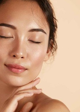 Frau mit geschlossenen Augen und strahlender Haut, steht für gesunde Feuchtigkeit und natürliche Pflege