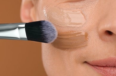 Make-up-Pinsel trägt leichte Foundation auf Wange auf, natürliche Deckkraft für ebenmässigen Teint