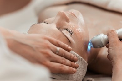 Eine liegende Frau lässt eine Gesichtsbehandlung beim Dermatologen machen