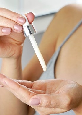Eine Frau gibt sich Niacinamid-Serum auf die Hände