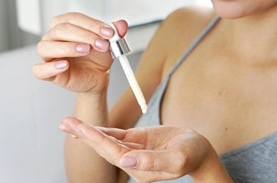 Eine Frau gibt sich Niacinamid-Serum auf die Hände