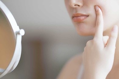 Mundpartie einer Frau, die ihren Finger auf die Wange hält